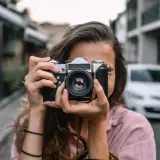 Dziewczyna z aparatem, idealna do kursu fotografii dla początkujących.