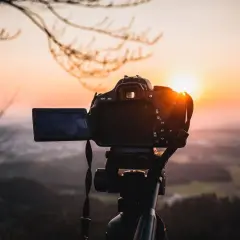 Aparat na statywie gotowy do uchwycenia zachodu słońca nad doliną. To idealne miejsce na **fotografię lotniczą**.