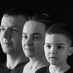 Trzy twarze w ujęciu monochromatycznym: mężczyzna, kobieta z warkoczami i chłopiec.