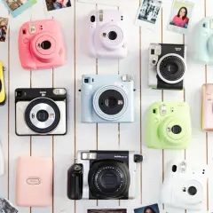Różne rodzaje aparatów Instax w jaskrawych kolorach: żółty, różowy, fioletowy, niebieski, zielony, biały, srebrny i pudrowy róż.