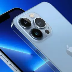 Zbliżenie na aparat iPhone 13. Trzy obiektywy i lampa błyskowa na jasnoniebieskim tle.