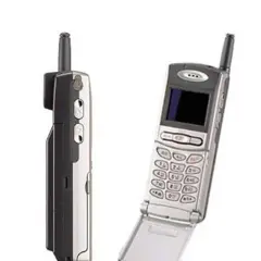 Dwa telefony komórkowe z lat 90. Jeden z nich to prawdopodobnie pierwszy telefon z aparatem, z charakterystyczną antenką i klapką.