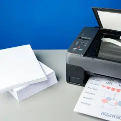 Stos białego papieru obok drukarki atramentowej, gotowy do drukowania. Jaki papier do drukarki atramentowej wybrać?