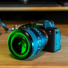Sony a7r5 z zielonym obiektywem na drewnianym stole.