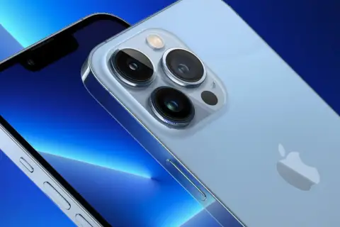 Zbliżenie na aparat iPhone 13. Trzy obiektywy i lampa błyskowa na jasnoniebieskim tle.