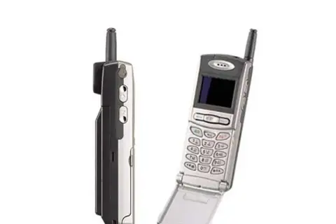 Dwa telefony komórkowe z lat 90. Jeden z nich to prawdopodobnie pierwszy telefon z aparatem, z charakterystyczną antenką i klapką.