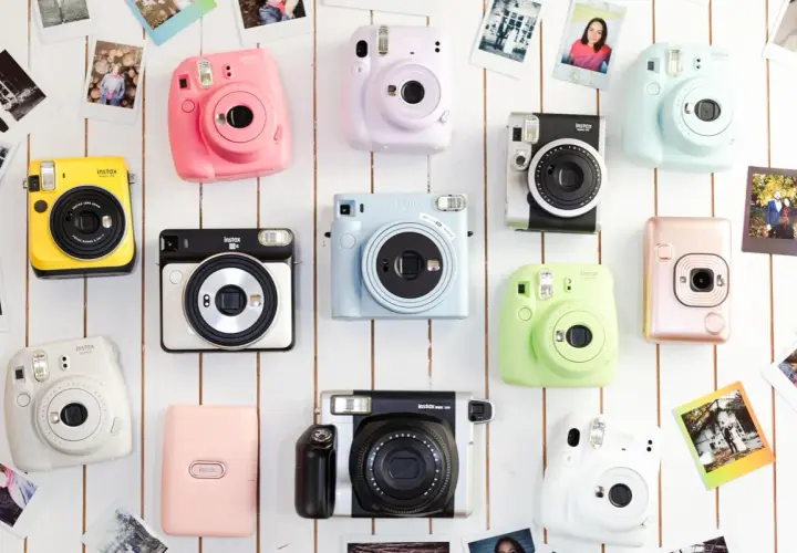 Różne rodzaje aparatów Instax w jaskrawych kolorach: żółty, różowy, fioletowy, niebieski, zielony, biały, srebrny i pudrowy róż.
