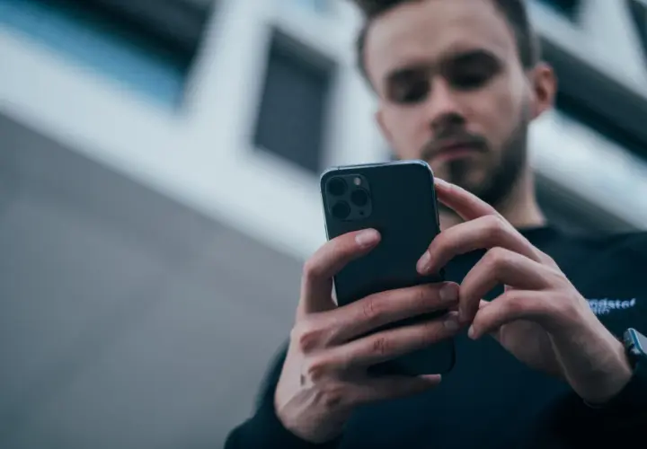 Mężczyzna z uwagą przegląda smartfon, zastanawiając się, jaki wybrać telefon.