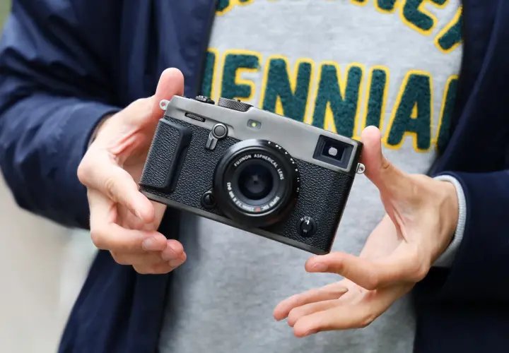 Dłonie trzymają aparat Fujifilm xpro3 z obiektywem.