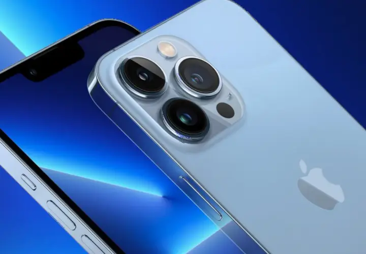 Zbliżenie na aparat iPhone 13. Trzy obiektywy i lampa błyskowa na jasnoniebieskim tle.