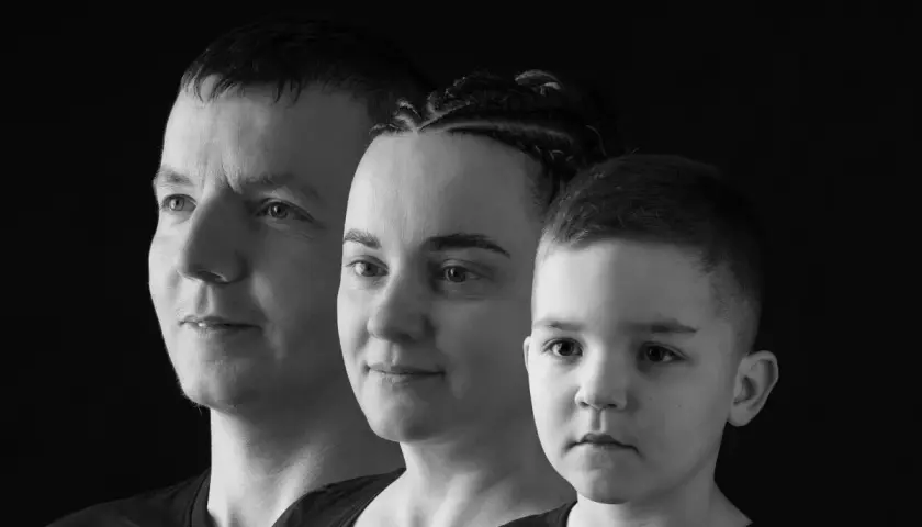 Trzy twarze w ujęciu monochromatycznym: mężczyzna, kobieta z warkoczami i chłopiec.