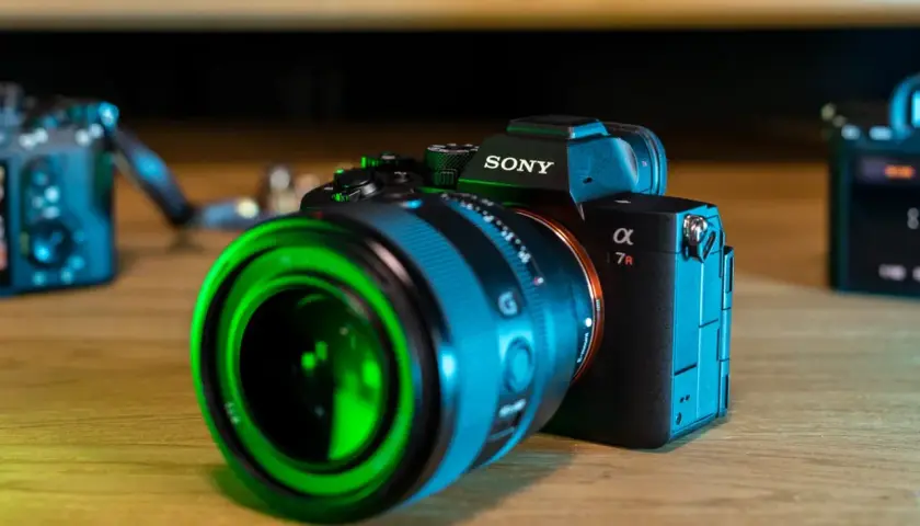 Sony a7r5 z zielonym obiektywem na drewnianym stole.