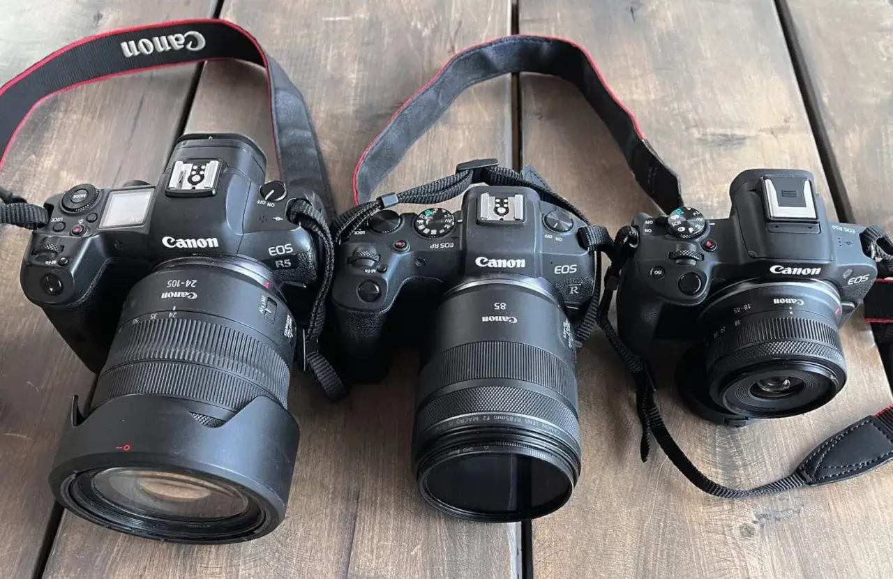 Trzy aparaty Canon EOS: R5, RP i R50, każdy z innym obiektywem. Pełna klatka i mniejsze modele gotowe do akcji.