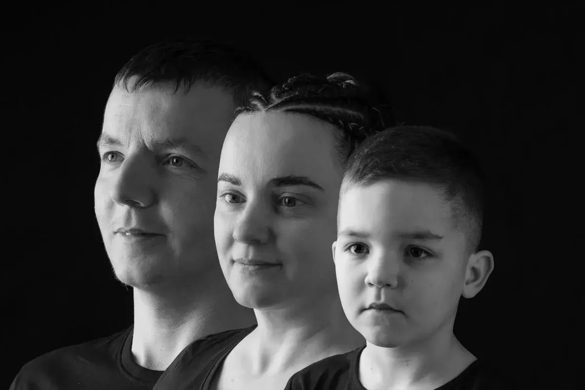 Trzy twarze w ujęciu monochromatycznym: mężczyzna, kobieta z warkoczami i chłopiec.