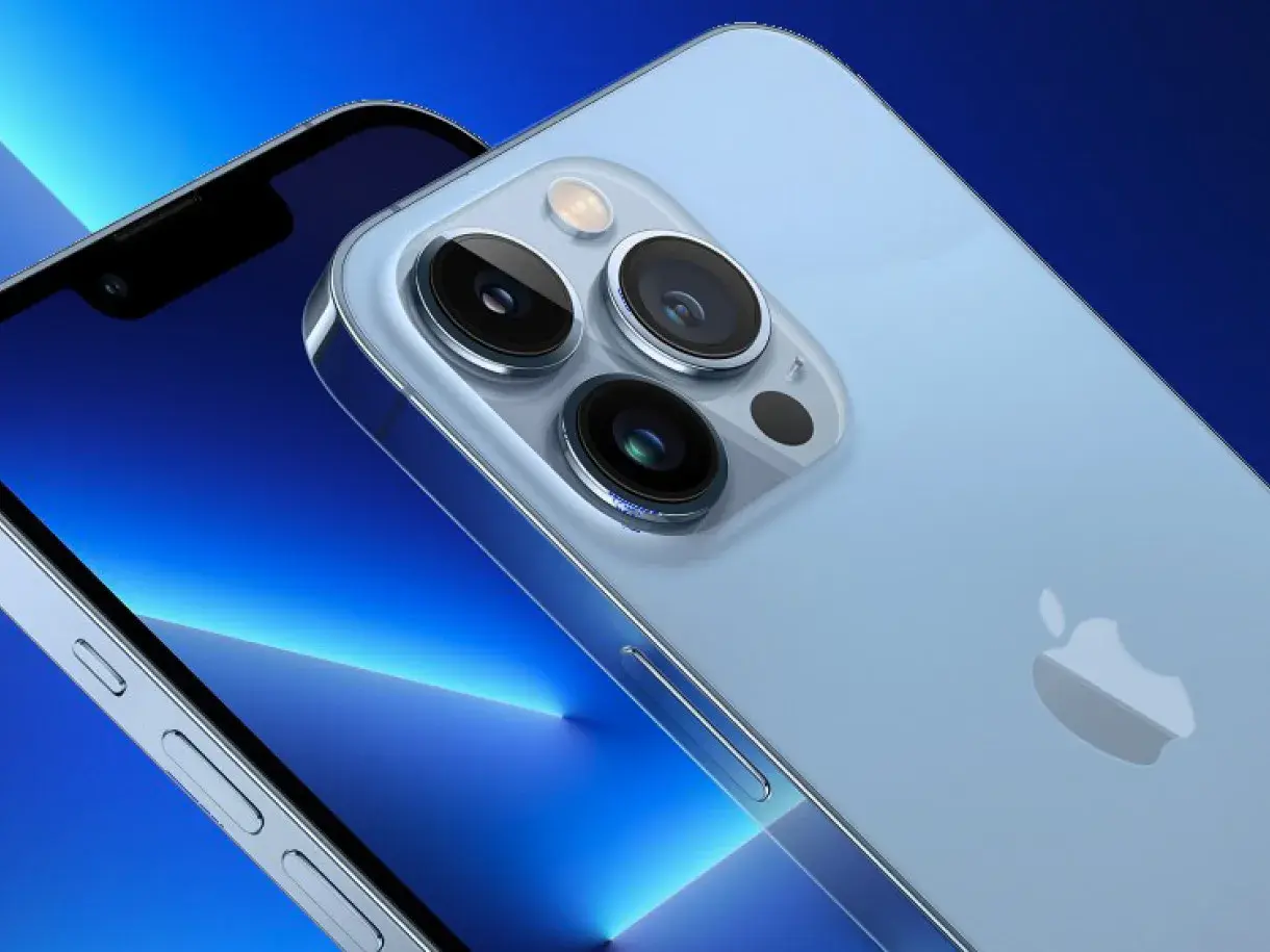 Zbliżenie na aparat iPhone 13. Trzy obiektywy i lampa błyskowa na jasnoniebieskim tle.