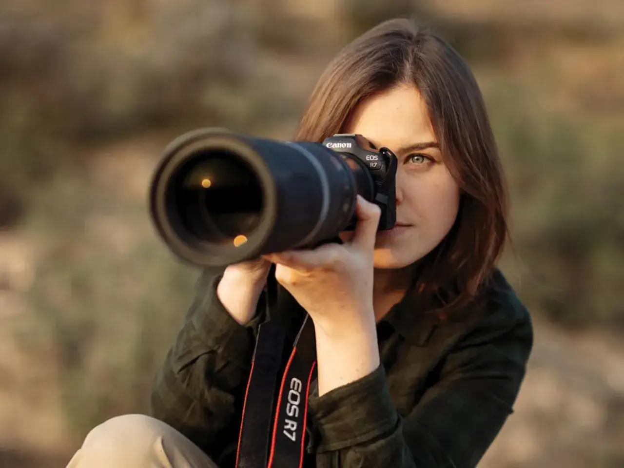 Portret kobiety z aparatem Canon EOS R7, gotowej do uchwycenia idealnego ujęcia.