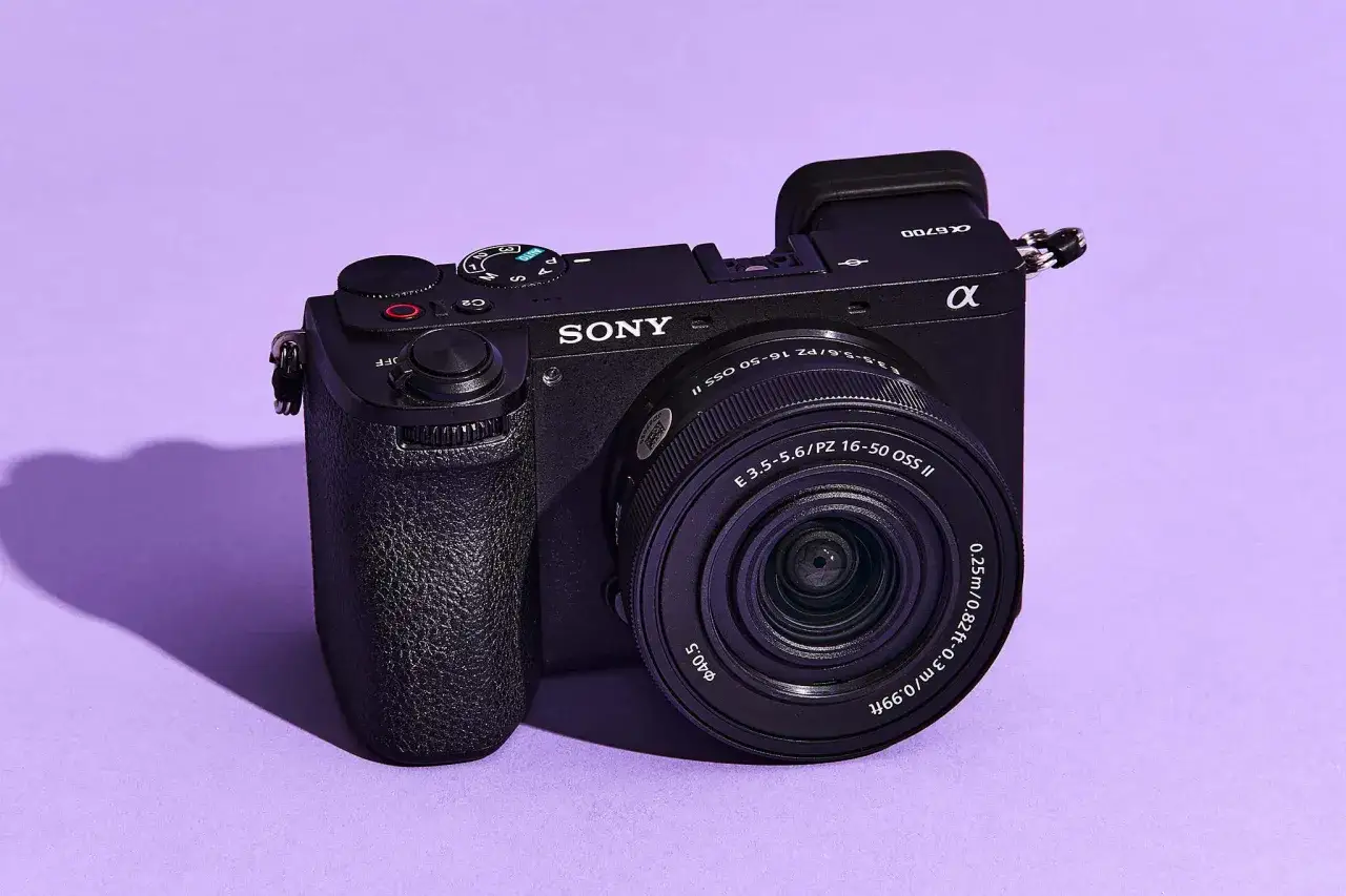 Czarny aparat Sony α6700 z obiektywem 16-50 mm, idealny do fotografii podróżniczej, na fioletowym tle.